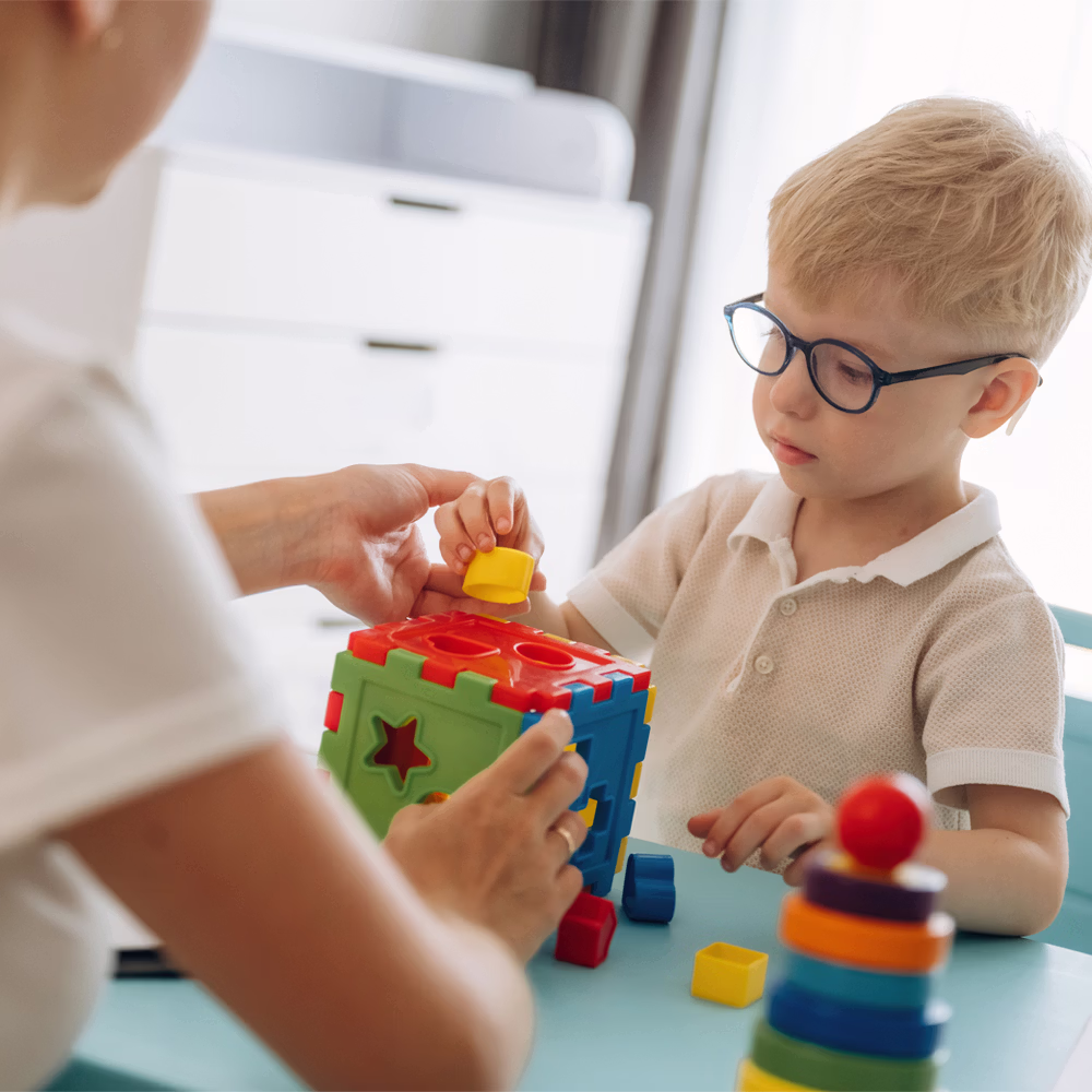 pathologist and young boy with glasses working on a puzzle